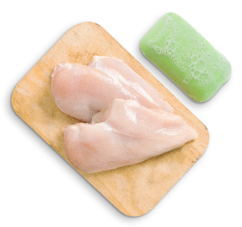 piece of raw chicken, soap and cutting board representing proper food handling, preparing and storing